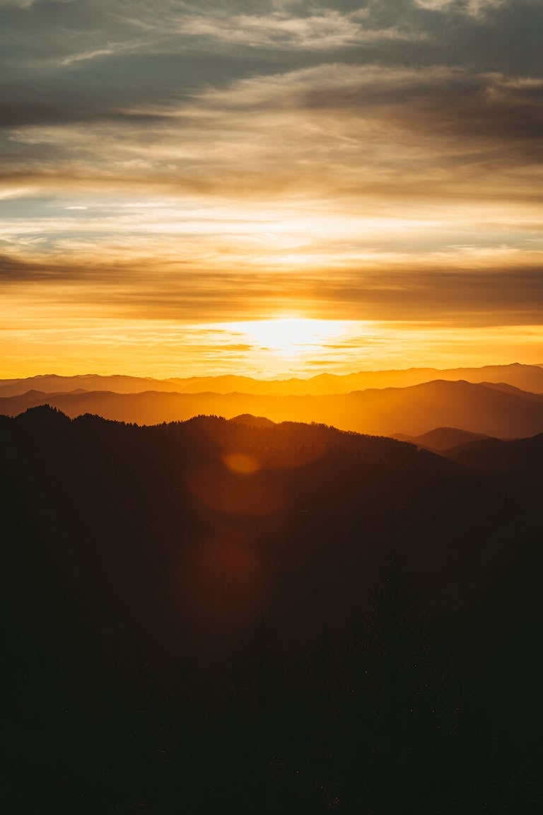 A breathtaking sunset casting golden hues over serene mountain peaks, creating a tranquil and awe-inspiring landscape.